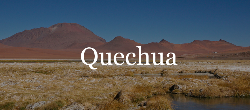 A grassland with large red mountains in the background, overlaid with Quechuan text