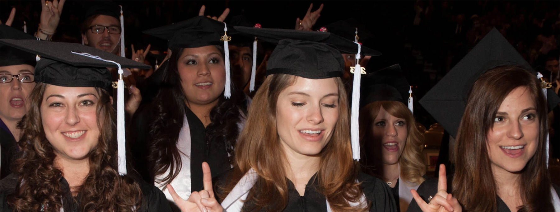 a group of graduating students in caps and gowns smiling and posing for the camera