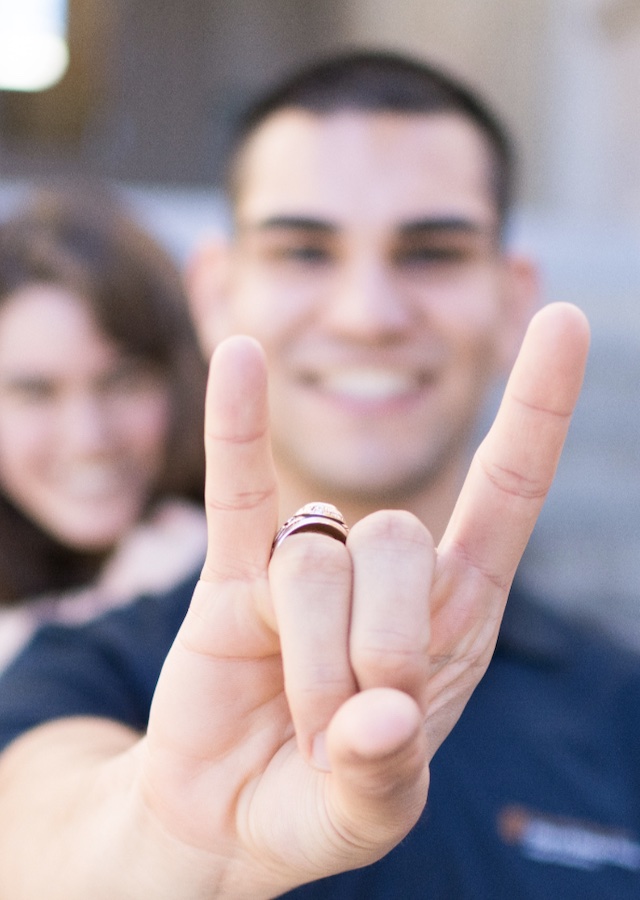 a student holds his hand close to the camera while making the hook 'em horns hand sign