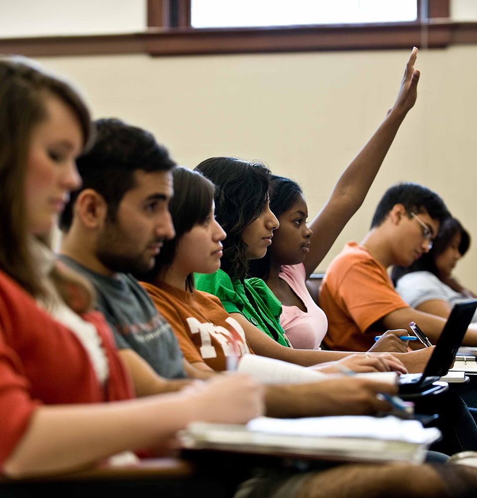 a row of students in a classroom listening to a lecture and taking notes